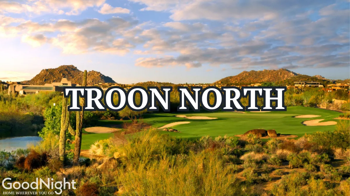 A panoramic view of a lush golf course framed by desert flora, with mountains rising in the background and a tranquil water feature in the foreground. The composition captures the serene beauty of Scottsdale’s signature desert golf experience.