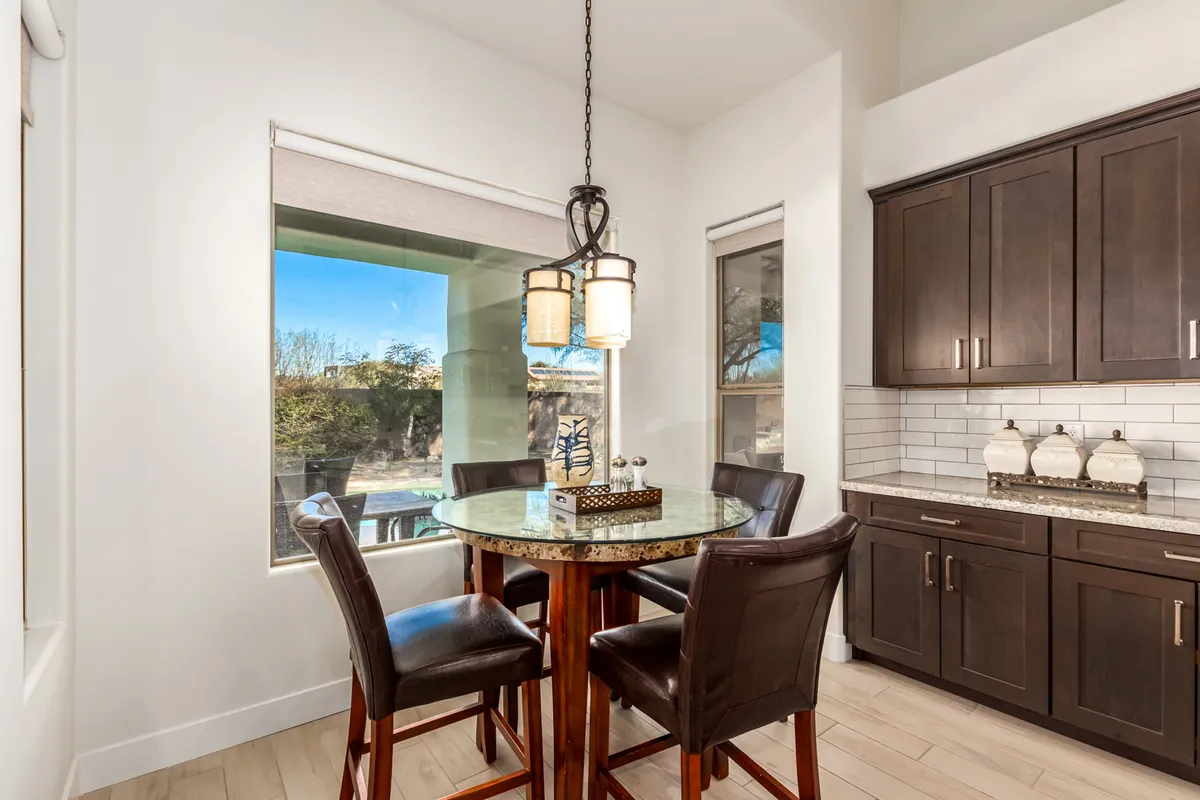 This photo showcases a welcoming dining area with a prominent dining table beneath an elegant chandelier. Large windows provide ample natural light, and the setup evokes an atmosphere ideal for both casual breakfasts and special-occasion dinners.