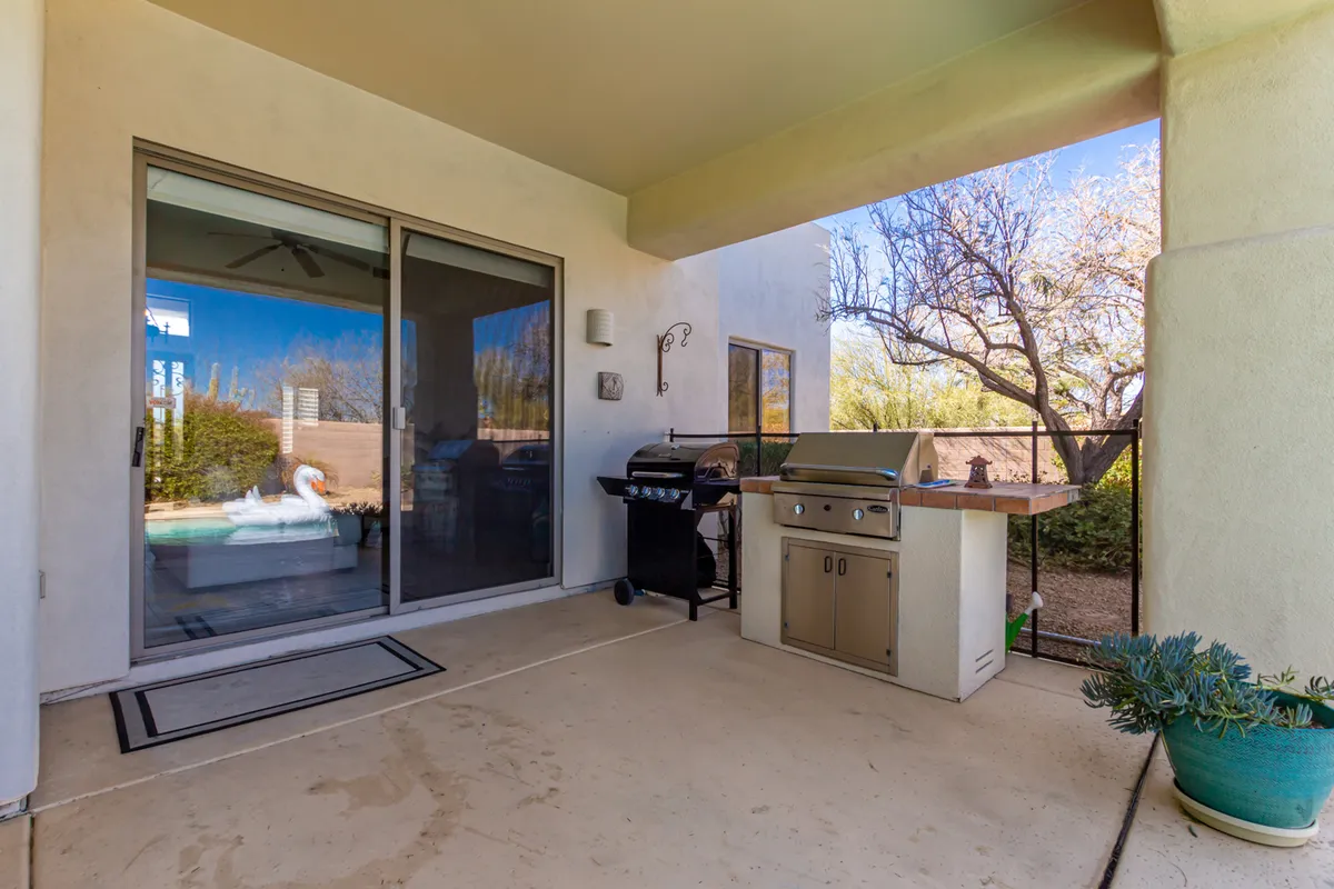 A stylish outdoor grill is the focal point of this patio scene, with a relaxed sitting area and a large sliding glass door connecting the outdoor and indoor living spaces. The setup is ideal for alfresco meals, summer parties, and easy entertaining.